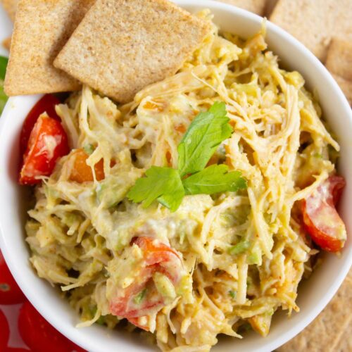 A bowl of healthy chicken salad with sliced cherry tomatoes, topped with cilantro.