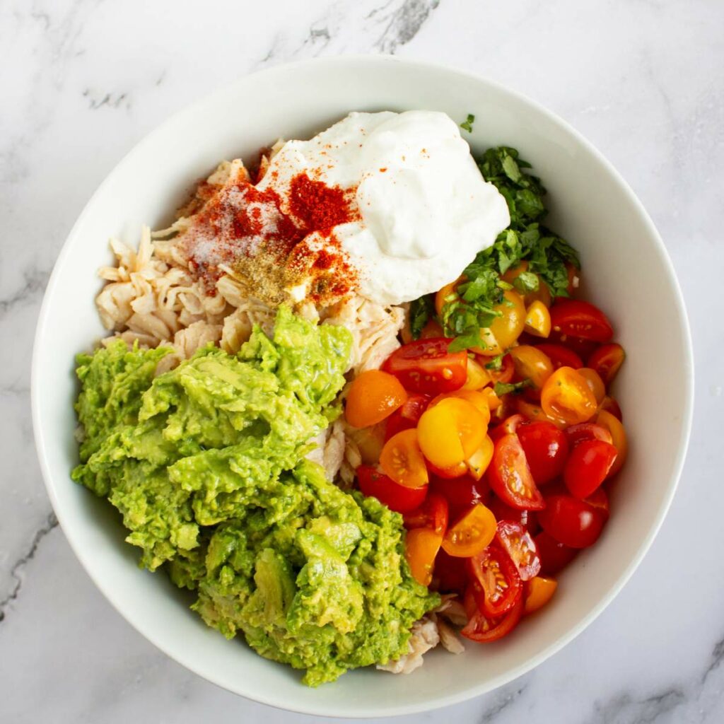 A white bowl containing shredded chicken and other ingredients.