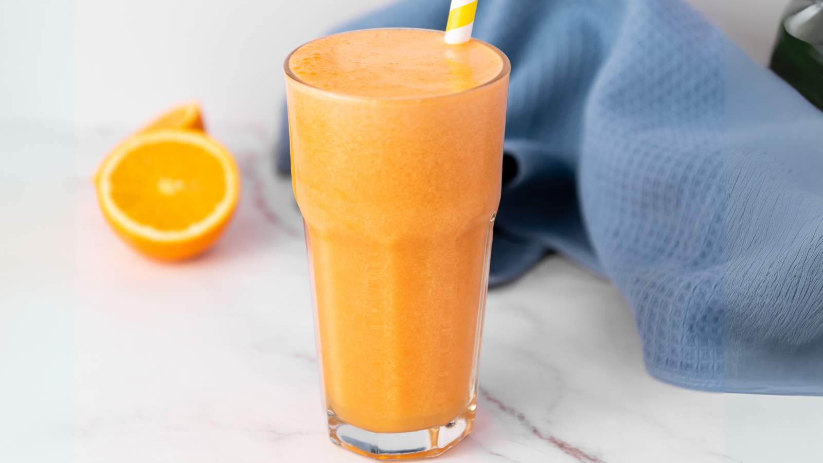A immunity boost juice with a yellow-striped straw sits on a white surface.