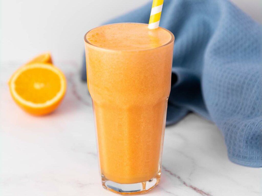 A glass of immunity boost juice with a yellow striped straw.