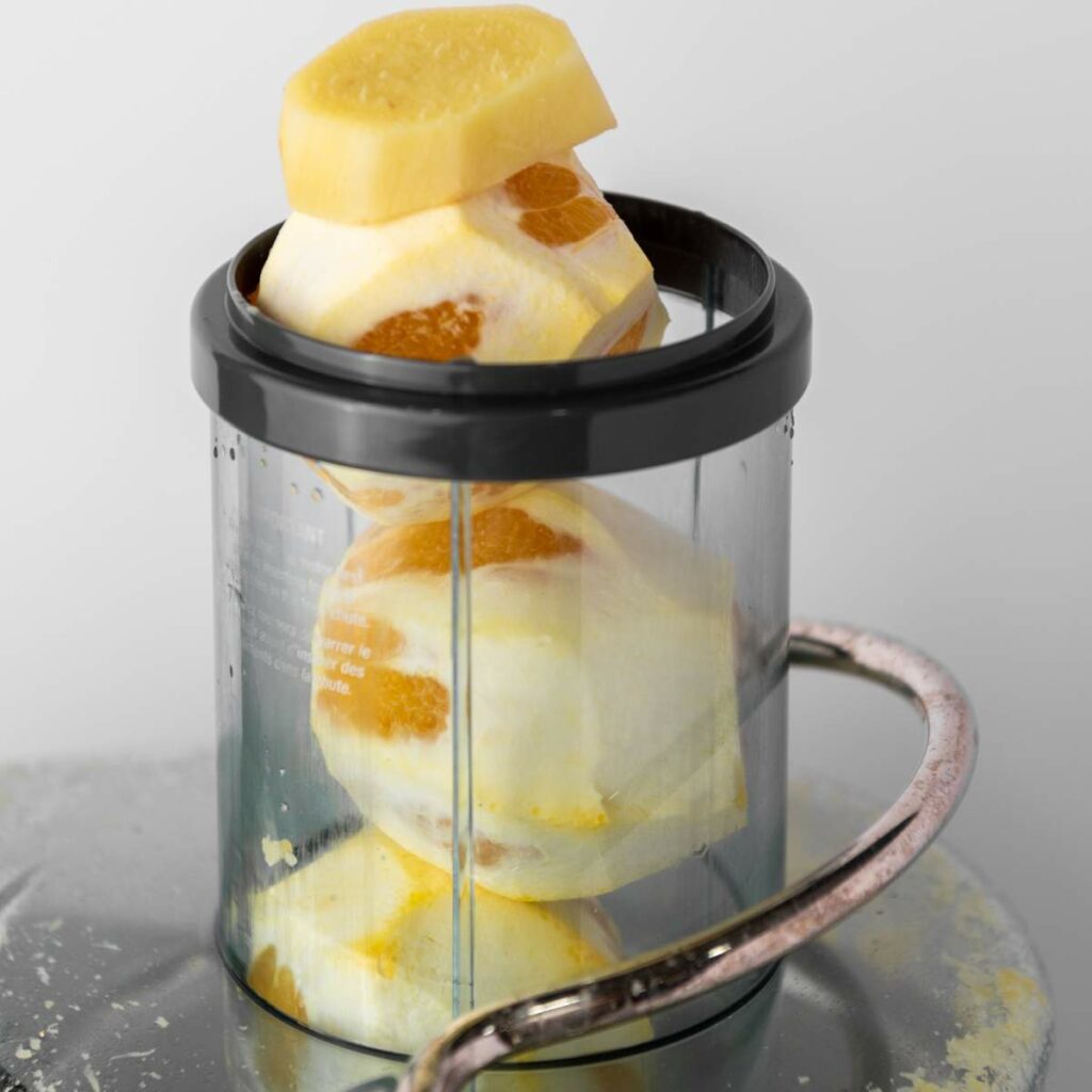 Several peeled ginger roots stacked inside a transparent container.