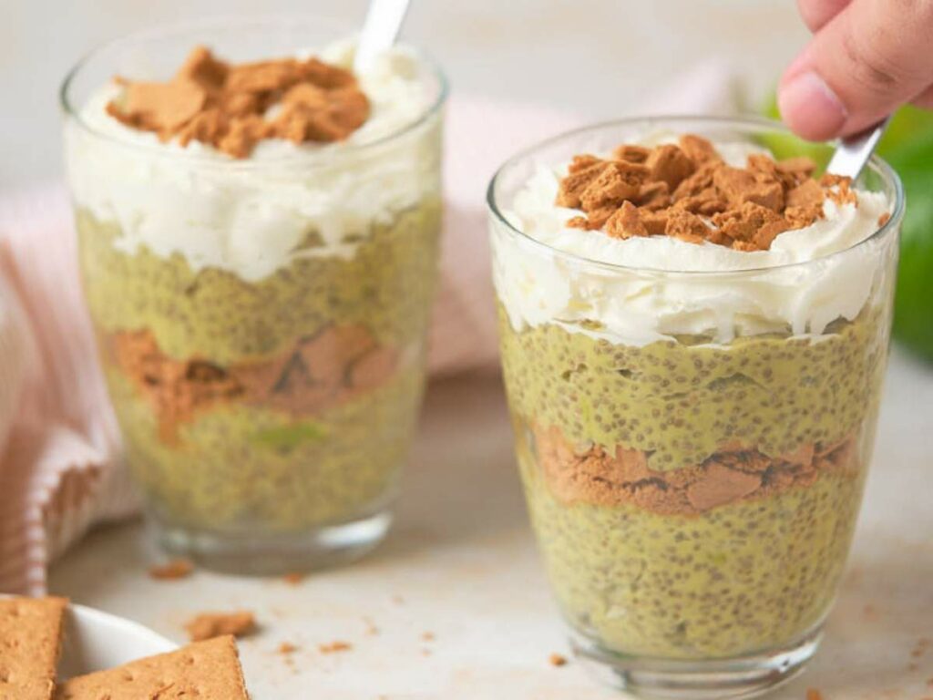 Avocado chia pudding served in glasses with a hand scooping a spoonful out of it.
