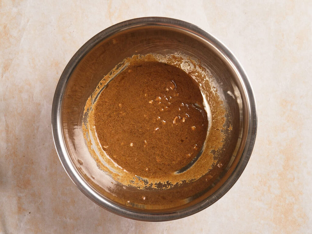 A stainless steel bowl containing a partially mixed brown batter.