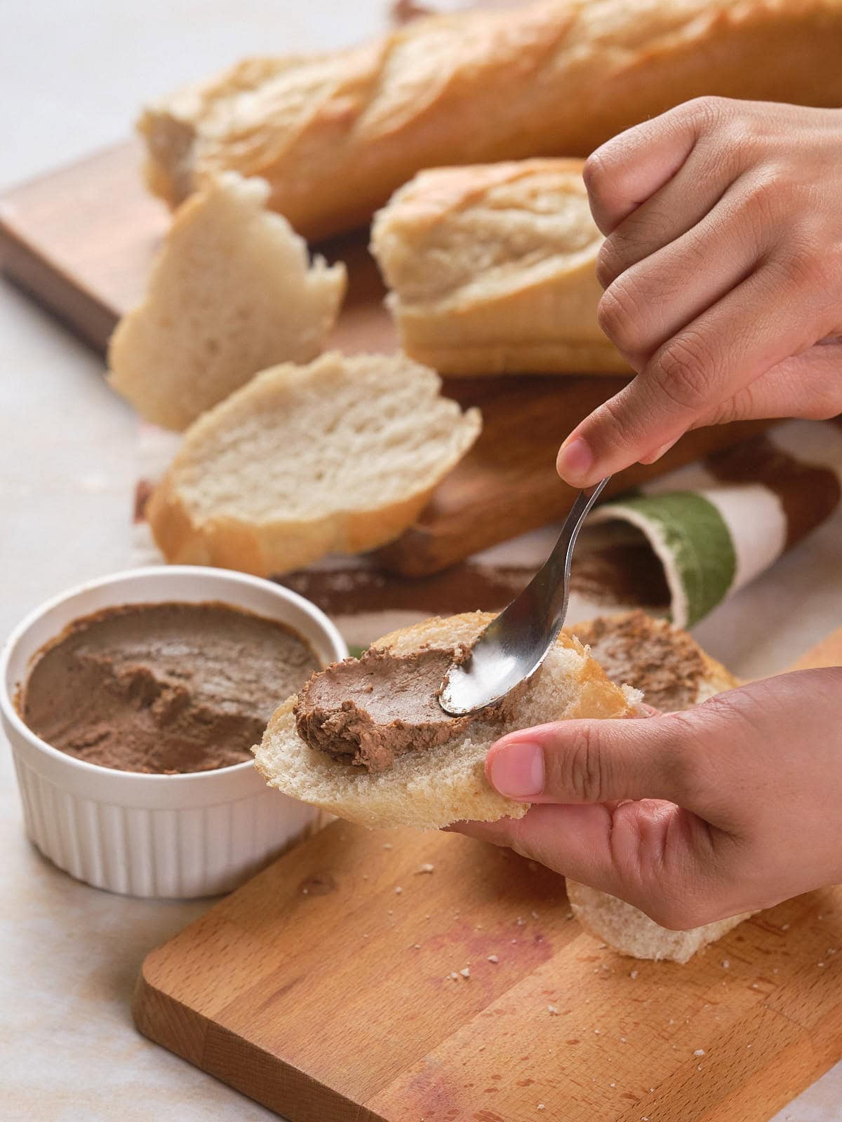 A person spreading beef liver pate on a slice of bread.