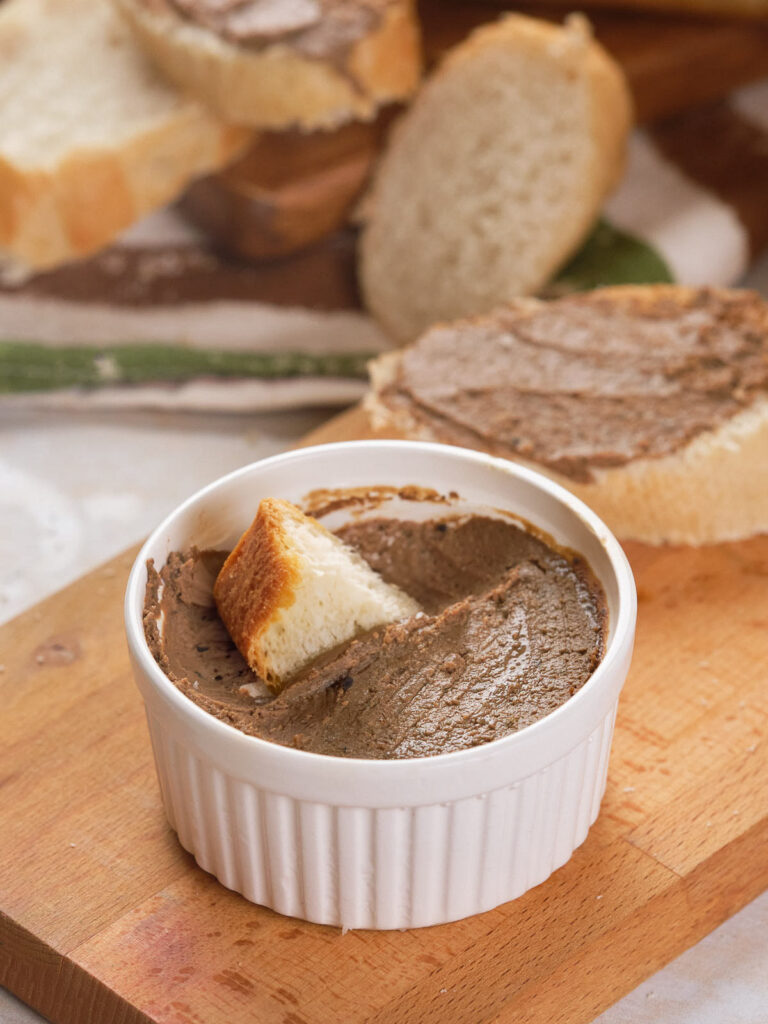 Bread inside a ramekin of beef liver pate.