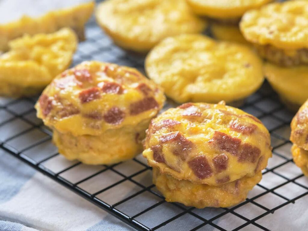 Golden, cheesy muffins studded with bits of meat are cooling on a wire rack, ready to be served.