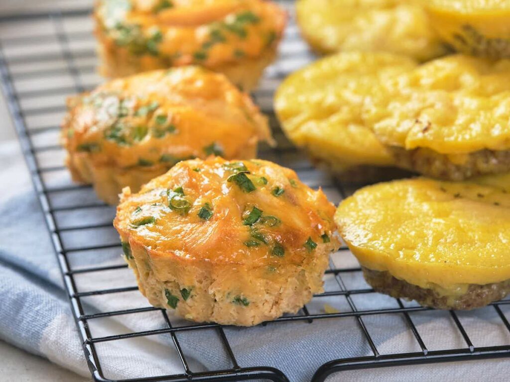 Golden, cheesy muffins with herbs cool on a wire rack.