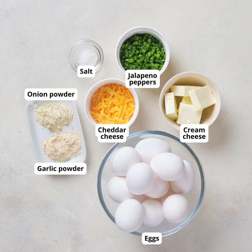 Flat-lay ingredients for egg muffins recipe are arranged on white surface.