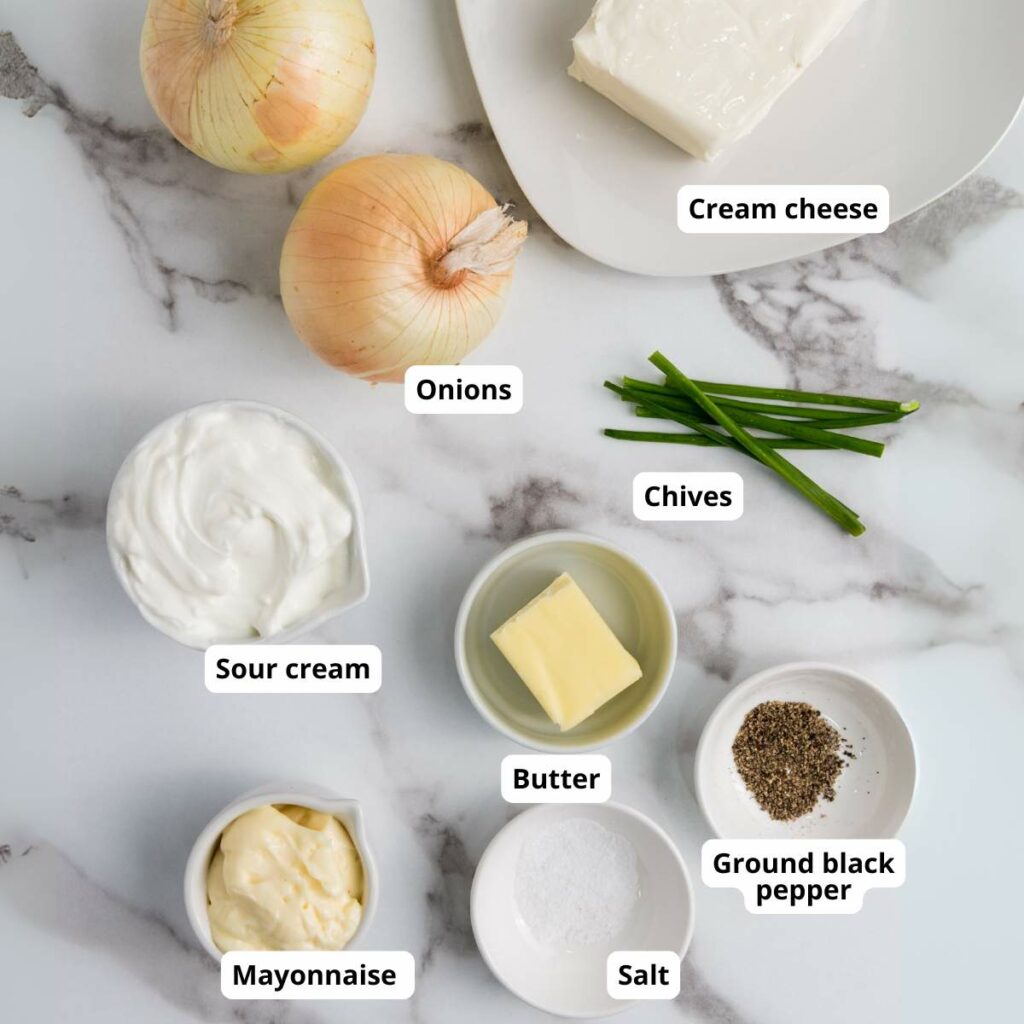 Labeled ingredients for a homemade french onion dip recipe on a marble surface.