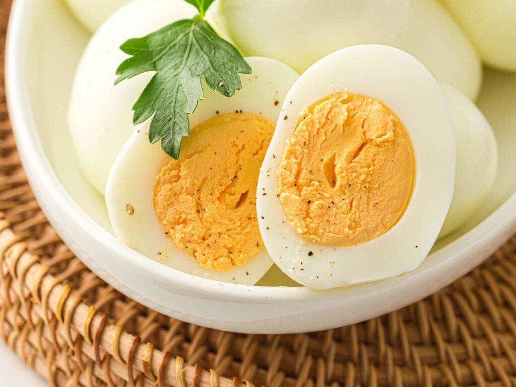 A bowl of hard-boiled eggs, with one egg cut in half to show the yolk.
