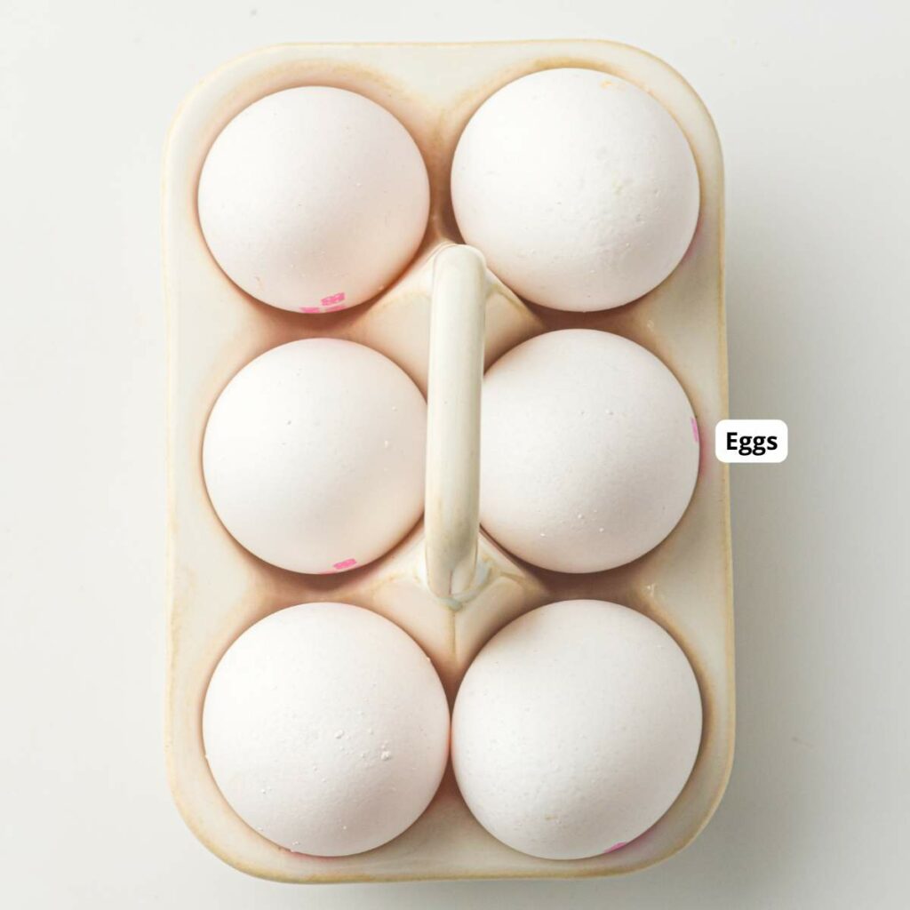 Six white eggs in a ceramic egg holder, viewed from above on a white background.