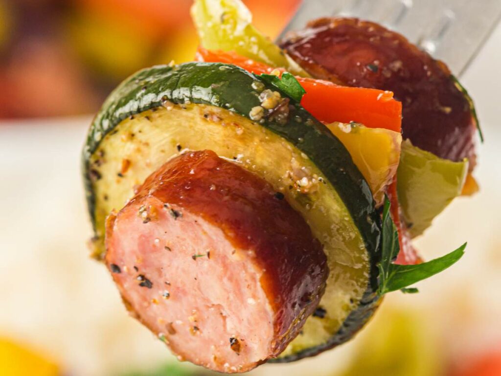 A forkful of sausage, zucchini, and peppers are being lift.