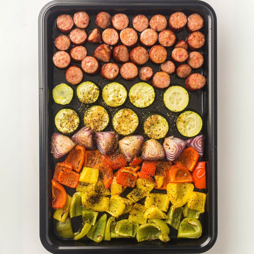 The same baking sheet shows roasted sausage and vegetables seasoned and ready to serve.