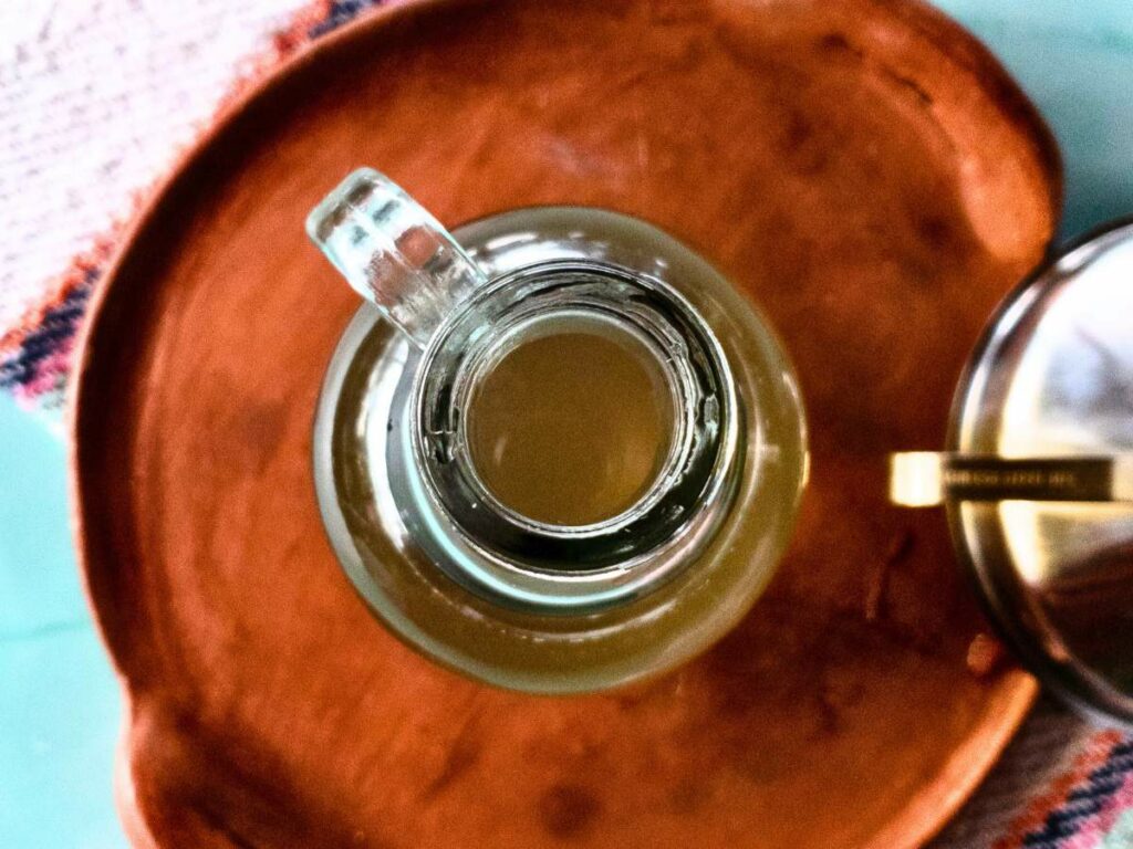 A glass jar of homemade simple syrup recipe on a wooden tray.