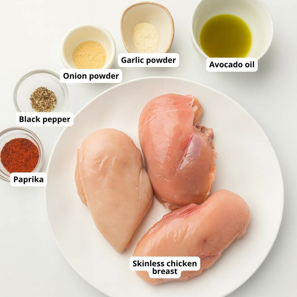 Ingredients for air fryer chicken breast are arranged on a white surface.