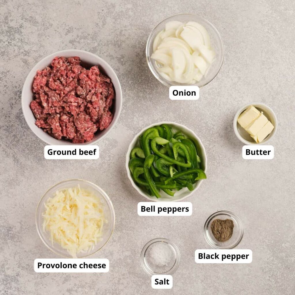 Bowls containing ground beef, sliced onion, bell peppers, provolone cheese, butter, salt, and black pepper.