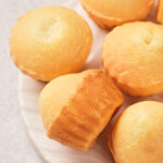 A close-up of several golden brown muffin cakes arranged on a white plate.