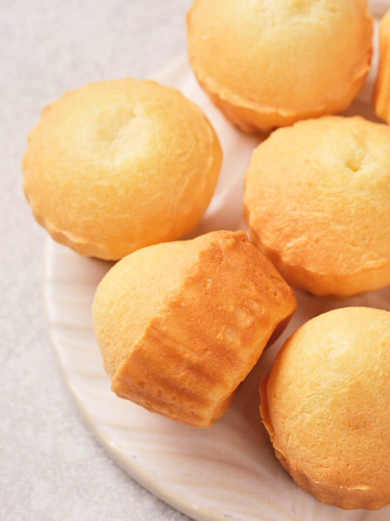 A close-up of several golden brown muffin cakes arranged on a white plate.
