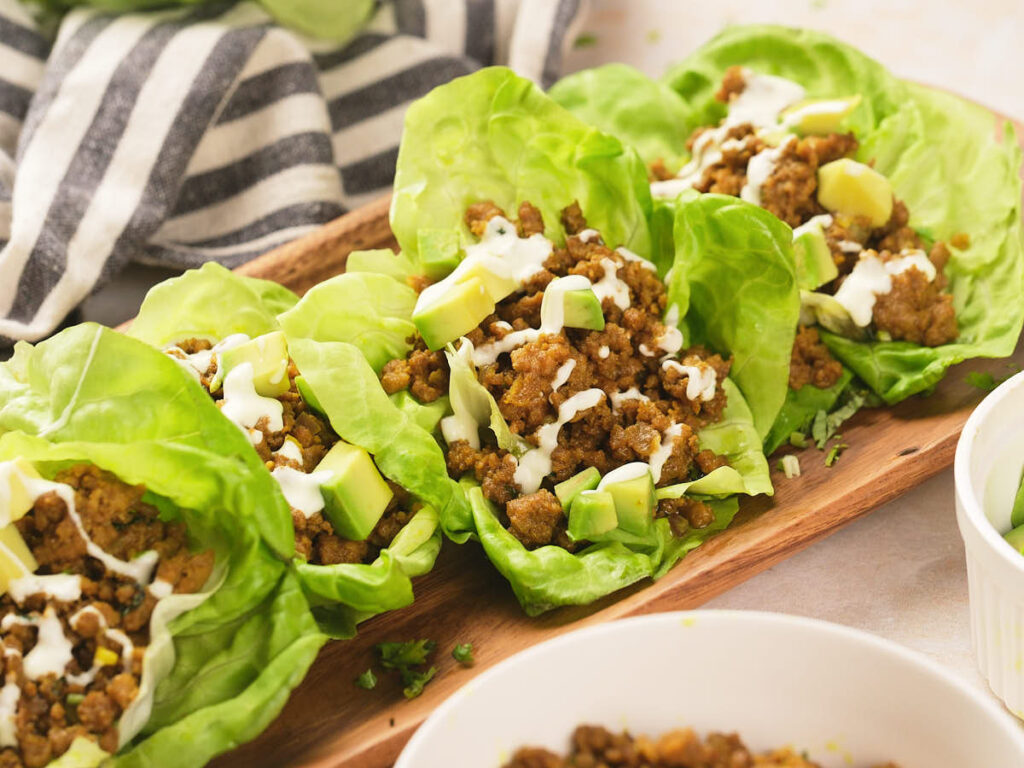 Four lettuce wraps filled with seasoned ground beef, diced avocado.