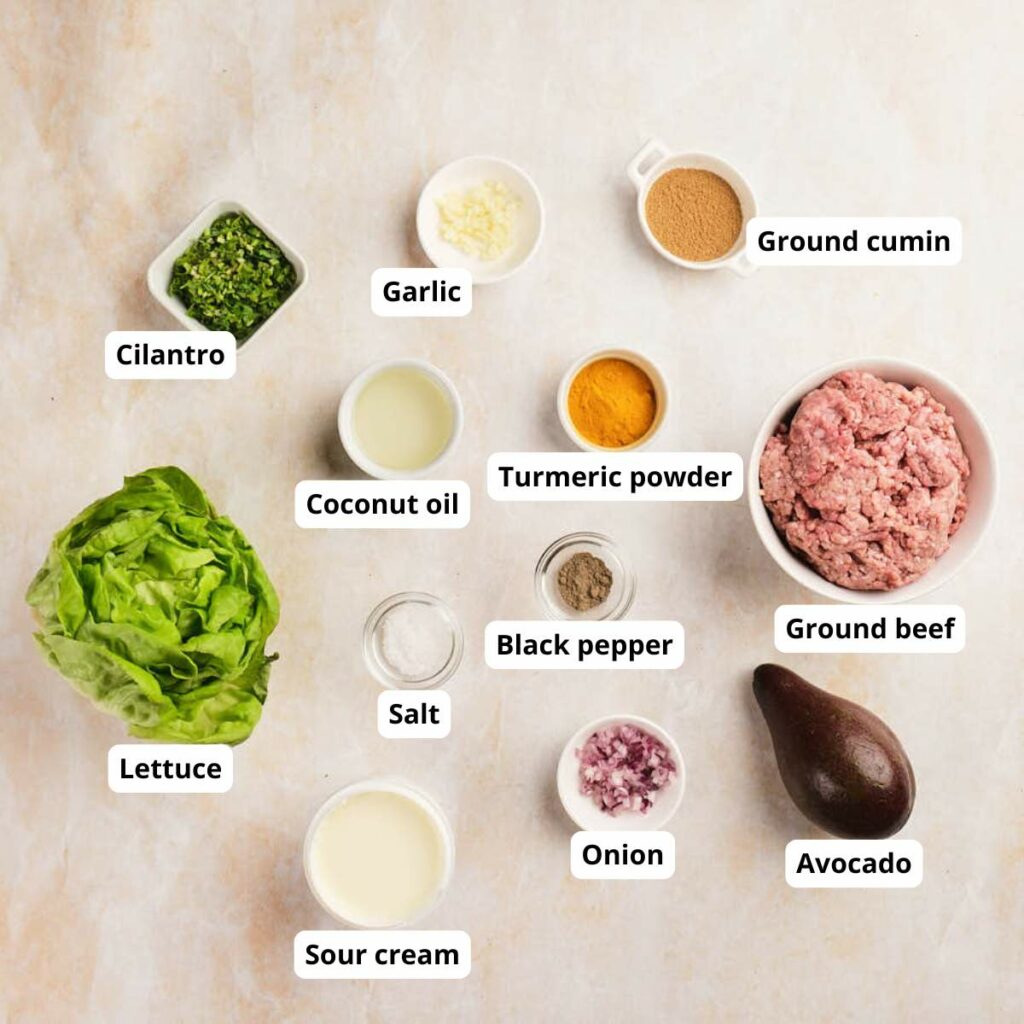 A variety of labeled ingredients for ground beef lettuce wraps on a light surface.