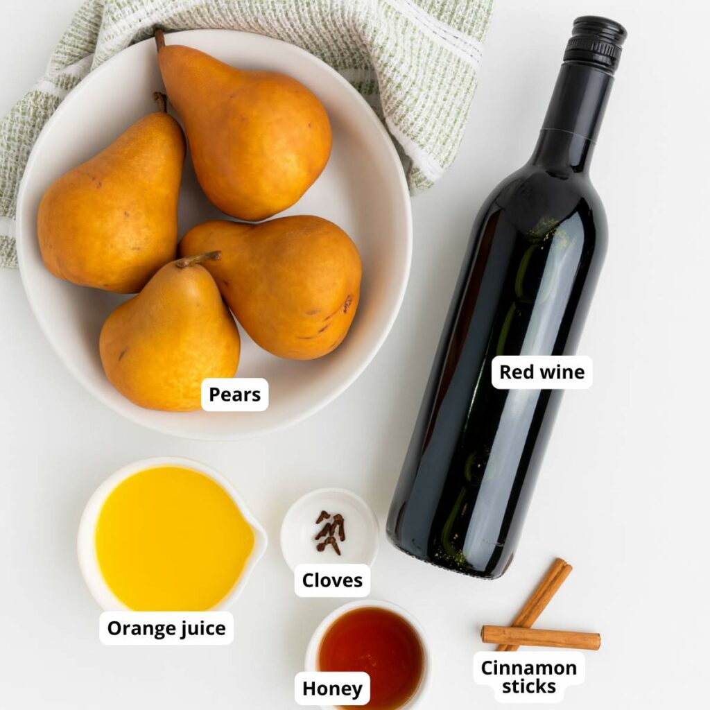Ingredients for poached pear dessert are arranged on a white surface with labels.
