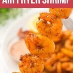 Skewered air fryer shrimp seasoned and cooked, with a dipping sauce and more shrimp in the background. Text reads "15-Minute Air Fryer Shrimp.