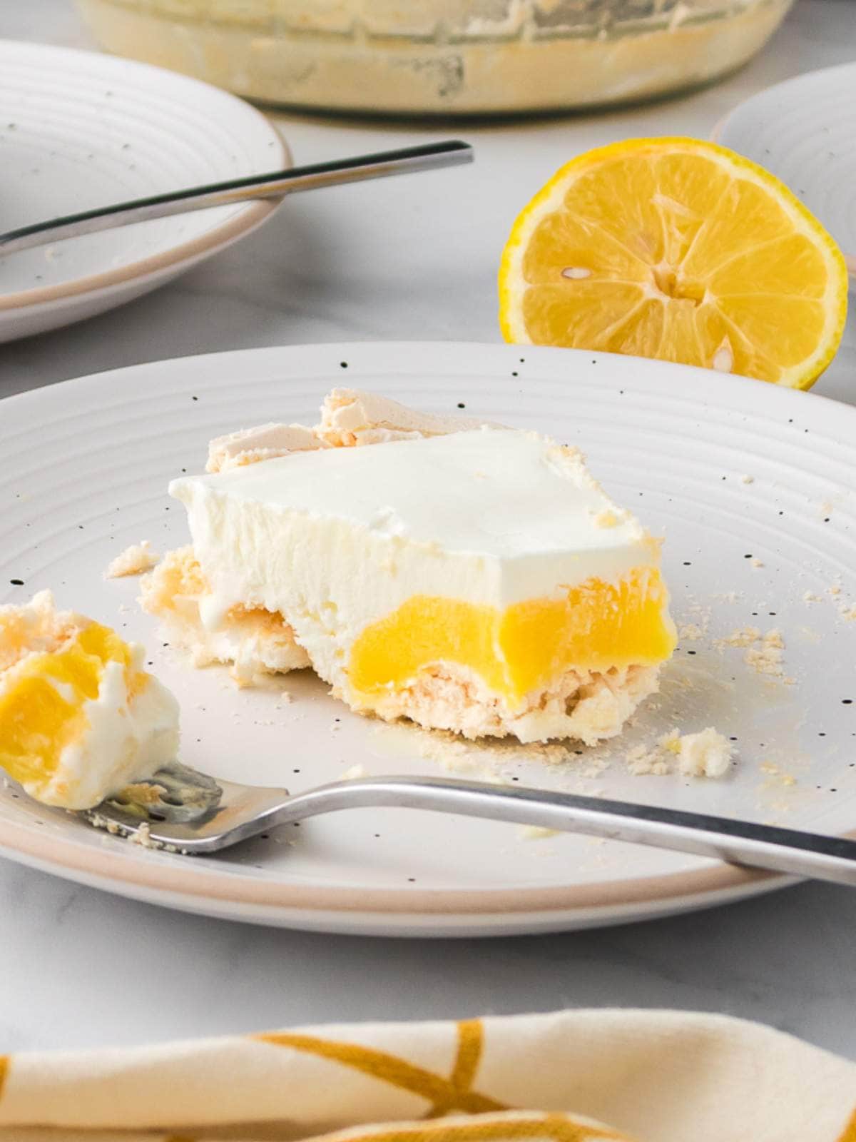 A slice of lemon dessert with a creamy layer and crumbly crust on a white plate.