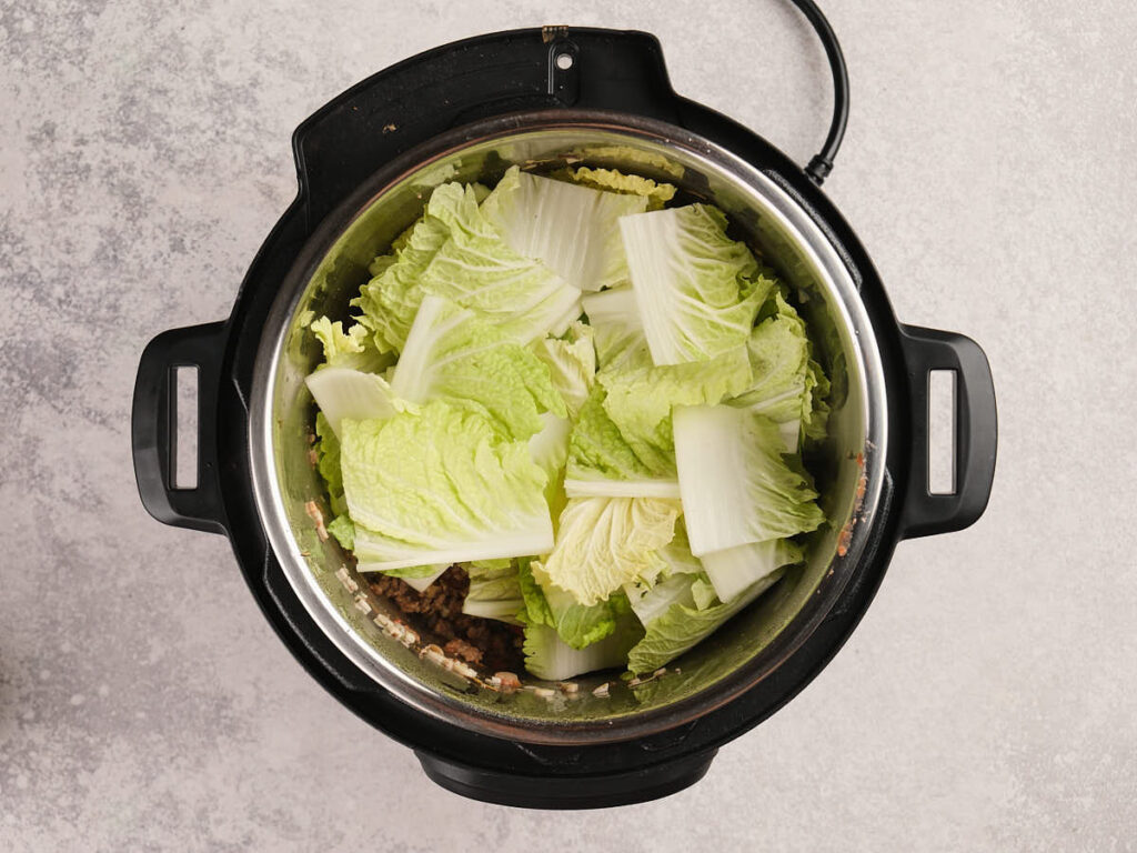 Fresh napa cabbage and ground beef inside an Instant Pot for healthy meal preparation.