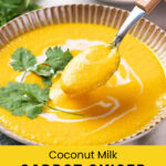 A bowl of coconut milk carrot ginger soup, garnished with cilantro and coconut milk, with a spoon lifting a portion.