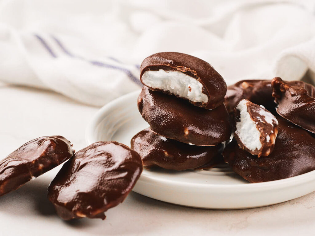 A plate of chocolate-covered candies with white creamy filling, some whole and some bitten.