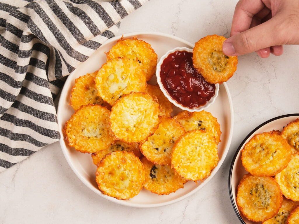 A plate of pickle chips next to a small bowl of red dipping sauce.
