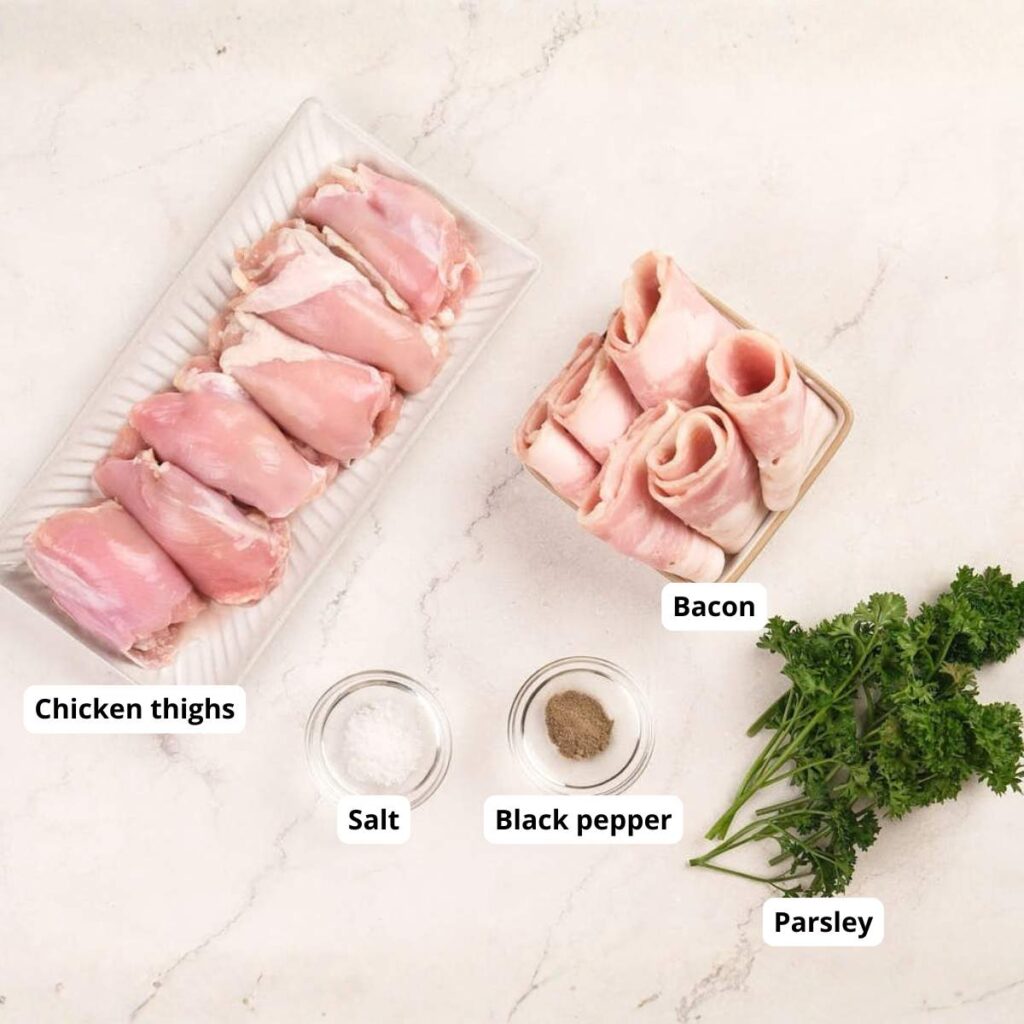 Raw chicken thighs, slices of bacon, salt, black pepper, and fresh parsley arranged on a light-colored countertop.