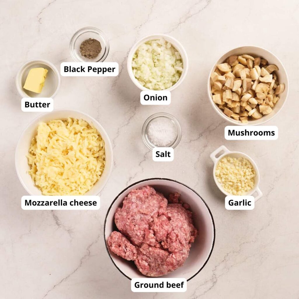 Ground beef, mozzarella cheese, butter, black pepper, onion, mushrooms, salt, and garlic, each in separate bowls.