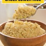 A wooden bowl filled with keto cauliflower rice, with a spoon lifting a portion. Text on image reads "Keto Cauliflower Rice" and "www.primaledgehealth.com".