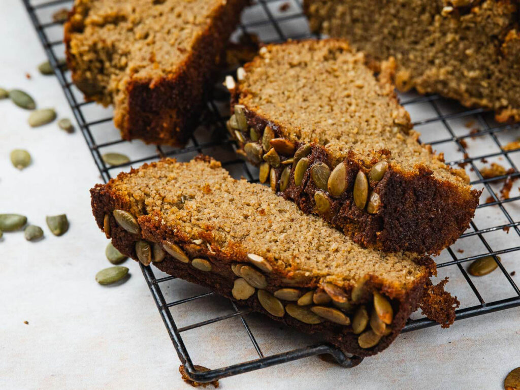 Slices of pumpkin seed bread on a wire cooling rack.