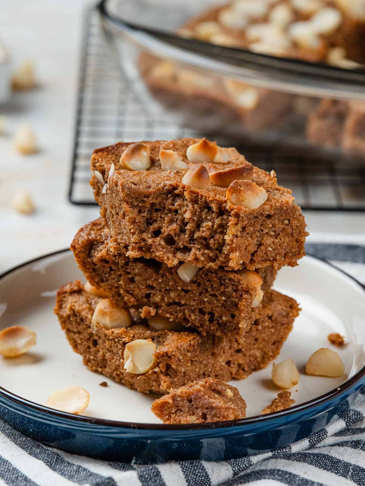 A stack of three brown sugar blondies topped with macadamia nuts on a small plate.