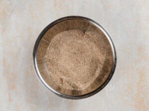 A stainless steel bowl filled with finely ground grain.