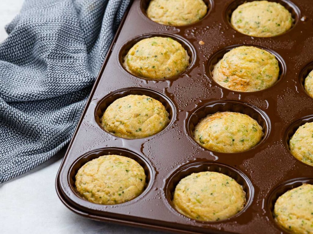 Freshly baked zucchini muffins in a brown silicone muffin pan.